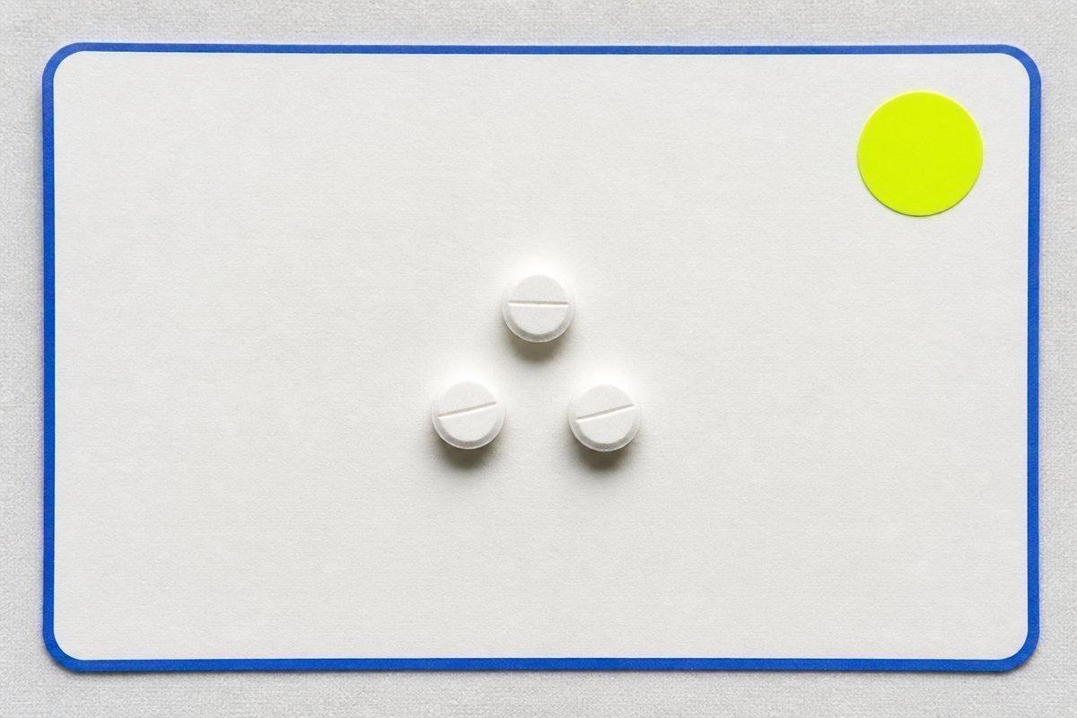 Bone review card, cobalt edge, lime chip: three small 3 mg tablets on a bone card