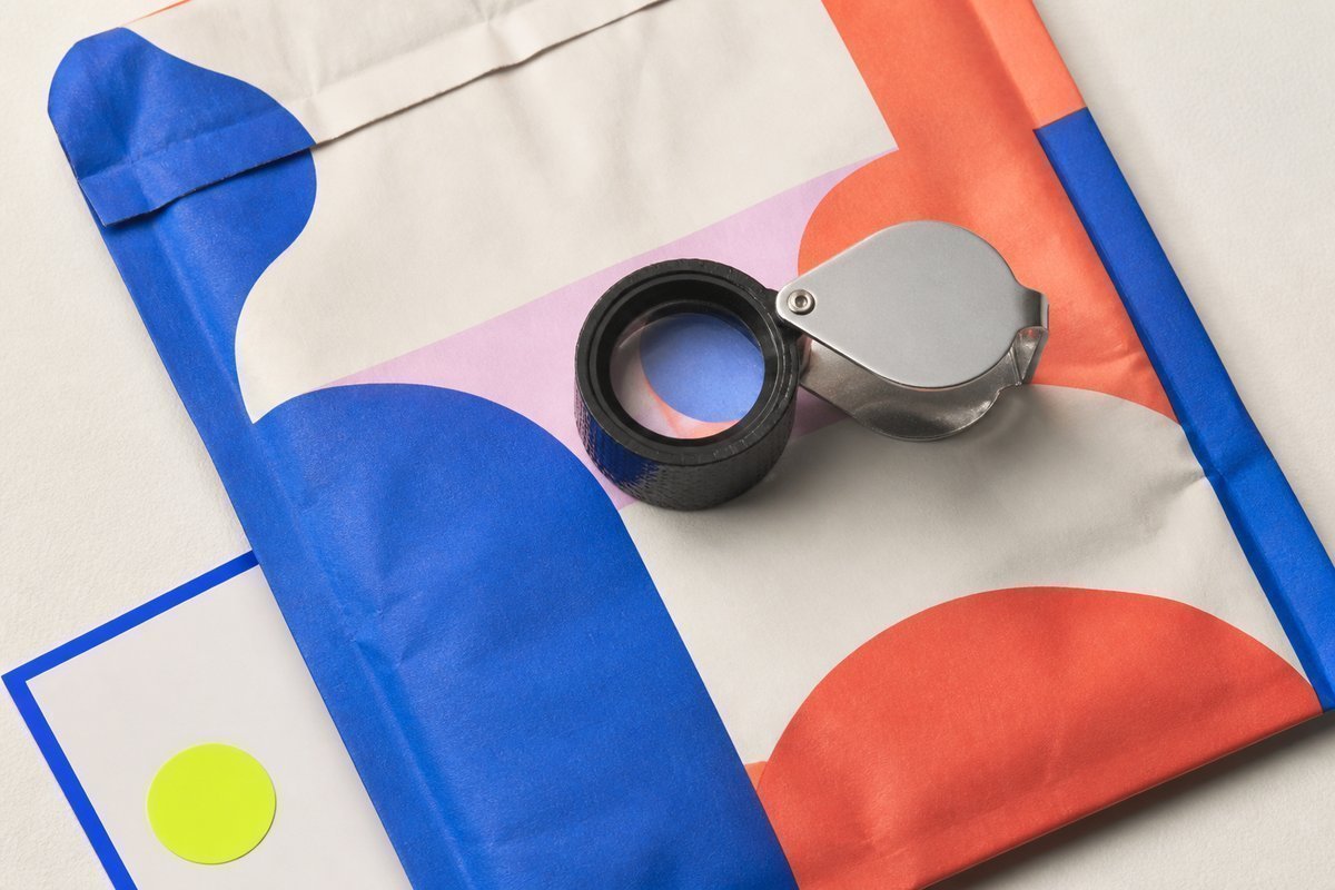 Bone review card, cobalt edge, lime chip: loupe on a colorful export mailer